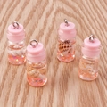 Vista macro de cuatro mini botellas de vidrio con tapones rosas y conchas para joyería DIY - Rosa