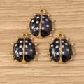 Three golden ladybug charms with black and white spots on a light wood background - 10 Pieces Pack / Black Ladybug