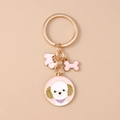 Vue détaillée du porte-clés chien doré avec breloques caniche en émail rose - Teddy Rose
