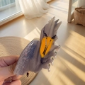 Hand holding a large acetate shoebill stork hair claw clip with grey marble texture - Vulture
