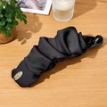 Eleganter Bananen-Haarclip aus schwarzem Plissee-Stoff auf einem stilvollen Holztisch - Schwarz Stoff