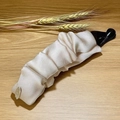 Eleganter plissierter Bananen-Haarclip aus champagnerfarbenem Stoff auf Holzstruktur - Beiger Stoff