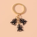Detailed view of three black spider charms on a golden metal keychain ring - Black