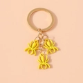 Detailed macro shot of three bright yellow spider charms on a golden metal keychain link - Yellow