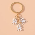 Detail of three white spider charms hanging from a polished gold keyring loop - White