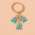 Detail view of gold metal keychain with three 3D light blue spider charms and matte finish - Light Blue