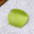 Lebendige grüne Haarklammer im Tennisball-Design auf weißem Spitzenstoff-Hintergrund - Grüner Tennisball