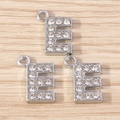 Macro shot of three silver rhinestone letter E charms on a light wood background - Letter E