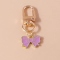 Close-up of purple enamel bow charm with gold lobster clasp for handbag decoration - Purple Bow