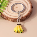 Dettaglio macro di un portachiavi a forma di banane gialle realistiche su legno - Banana