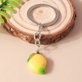Dettaglio di un portachiavi a forma di mango giallo realistico su sfondo in legno - Mango