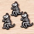 Close-up of black and white dinosaur skeleton alloy pendants on a light wood background - 5 Pieces / T-Rex Skeleton Style (1849)