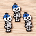 Detail view of 3 cartoon skeleton girl charms with blue hats on light wood background - 5 Pieces / Blue Star Hat Skull Boy