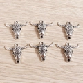 Detailed close-up of six vintage cow skull pendants with Bohemian patterns on wood background - Bull Skull / 15 Pcs Pack / Antique Silver