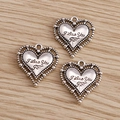 Dettaglio dei ciondoli a cuore in argento antico con incisione I Love You su sfondo di legno - Cuore