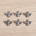 Detailed view of six vintage silver bee charms with hollow wings on a wood surface - Bee / 40Pcs Pack / Antique Silver