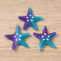 Detail of three purple gradient starfish charms with pearls and metal rings on wood - Blue and Purple
