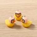 Close-up of cute yellow 3D duck charms with pink helmets for DIY jewelry making - Pink Helmet Duck Style