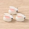 Three cute white resin bunny pendants with metal loops on a light wood background - 3D Rabbit Pendant (2533) / 10 Pieces Pack / White