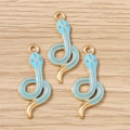 Macro detail of three light blue enamel snake charms with gold plating for jewelry making - Blue