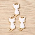 Trois breloques chat en émail doré et blanc avec queue bouclée sur fond de bois - Lot de 10 / Blanc