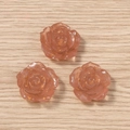 Detaillierte Makroaufnahme von drei Harzrosen in Rosé mit Goldfolie auf Holzgrund - Braun
