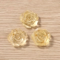 Drei transparente Rosen-Anhänger aus Harz mit Goldfolie auf hellem Holzhintergrund - Gelb