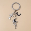 Dettaglio ravvicinato di portachiavi con croce argento, luna nera e nappina a stella - Stile Croce Luna Stella