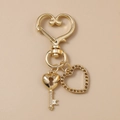 Dettaglio portachiavi a cuore dorato con ciondolo in strass su pelle strutturata - Stile Chiave Cuore Traforato