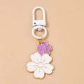Dettaglio di un portachiavi a fiori con ciliegi bianco e viola e bordi in metallo dorato - Fiore Bianco