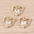 Macro view of three gold heart charms with clear faceted gems on light wood - Gold White