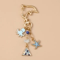 Llavero dorado de vida marina con dijes de pulpo y estrella de mar en fondo beige - Estrella de Mar Azul
