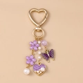 Detailansicht eines goldenen Herzverschlusses mit lila Glitzerschmetterling und Anhängern - Violetter Schmetterling