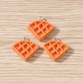 Three orange resin waffle charms with metal loops on a natural light wood background - Crepe / 10 Pieces Pack