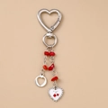 Detalle de llavero corazón plateado con dije de cereza esmaltada y piedras rojas - Corazón de Cereza