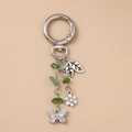 Vue détaillée du porte-clés en métal argenté avec perles vertes et pendentif papillon - Feuille Papillon