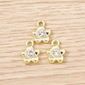 Macro view of three gold flower pendants with rhinestones on light wood background - Gold Rhinestone Flower