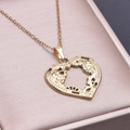 Makroaufnahme des 18k Gold Herzanhängers mit Zahnrädern auf rosa Schmuckschatulle - Halskette mit Anhänger / Gold