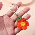 Handgefertigter gehäkelter Pflaumenblüten Schlüsselanhänger mit Blüte und grünem Blatt - Pflaumenblüten-Stil / Orange