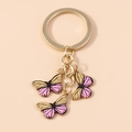 Vue macro de trois breloques papillons émaillés dorés avec dégradés rose et jaune - Jaune-Rose