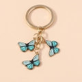 Détail macro de trois pendentifs papillon turquoise sur un porte-clés doré chic - Vert