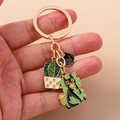 Detail view of cartoon black cat and cactus charms on a golden metal keychain pendant - Black Cat in Green Leaves Style (1453heimao)