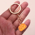 Gros plan sur un porte-clés doré avec pendentif citrouille en émail orange pour Halloween - Tête de Citrouille Jaune