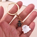 Macro shot of Halloween ghost and gingerbread man charms on a gold keychain - White Ghost