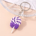 Macro view of a colorful spiral lollipop keychain with a purple bow and silver metal chain - Purple
