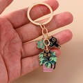Detailed look at gold enamel keychain featuring cartoon black cats and monstera charms - Green Clover Black Cat Style (1453lvhua)