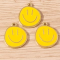 Three yellow smiley face alloy pendants with gold plating on light wood background - 10 Pieces Pack / Yellow