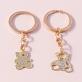 Dettaglio di portachiavi a forma di orso dorati con pavé di cristalli e cuori incisi - Set Orso