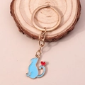 Dettaglio del portachiavi dorato con ciondolo gatto blu e cuore rosso su legno - Blu