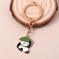 Portachiavi panda con anello in oro rosa e cappello di paglia su sfondo rosa tenue - Nero & Bianco
